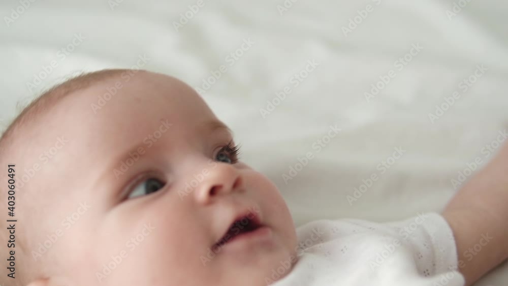 Closeup little sweet baby lying on bed and calling mommy, trying to catch camera Closeup little sweet baby lying on bed and calling mommy, trying to catch camera