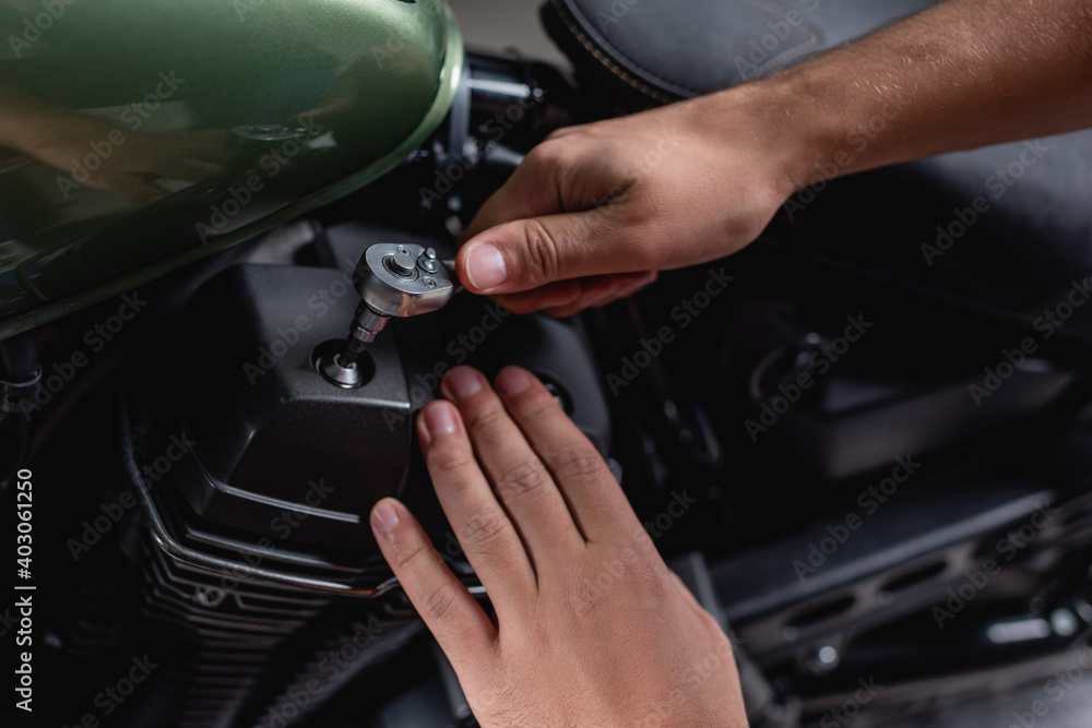 cropped view of mechanic using socket wrench while making diagnostics of motorcycle in workshop cropped view of mechanic using socket wrench while making diagnostics of motorcycle in workshop