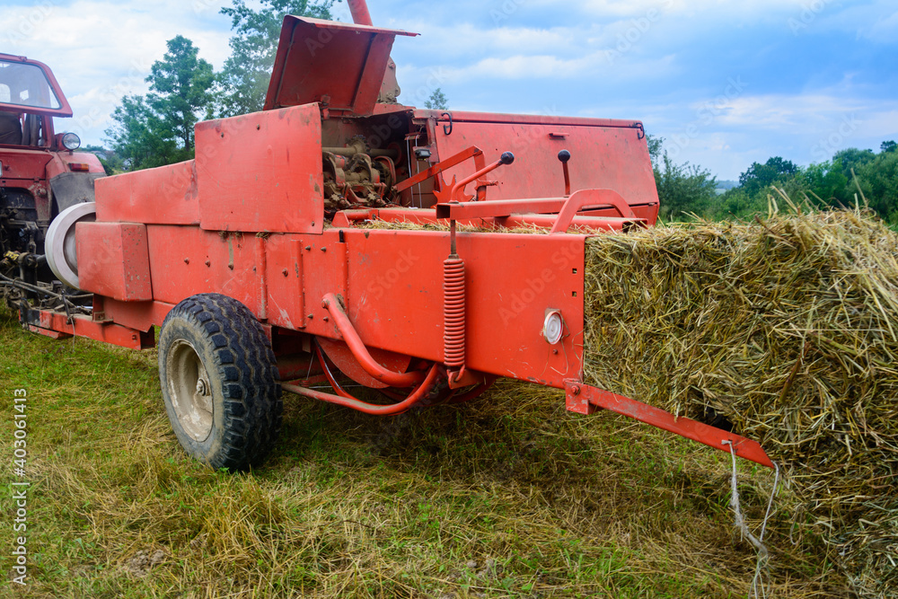 Old bale press, hay harvesting in the village for cattle, press work close up. Old bale press, hay harvesting in the village for cattle, press work close up.