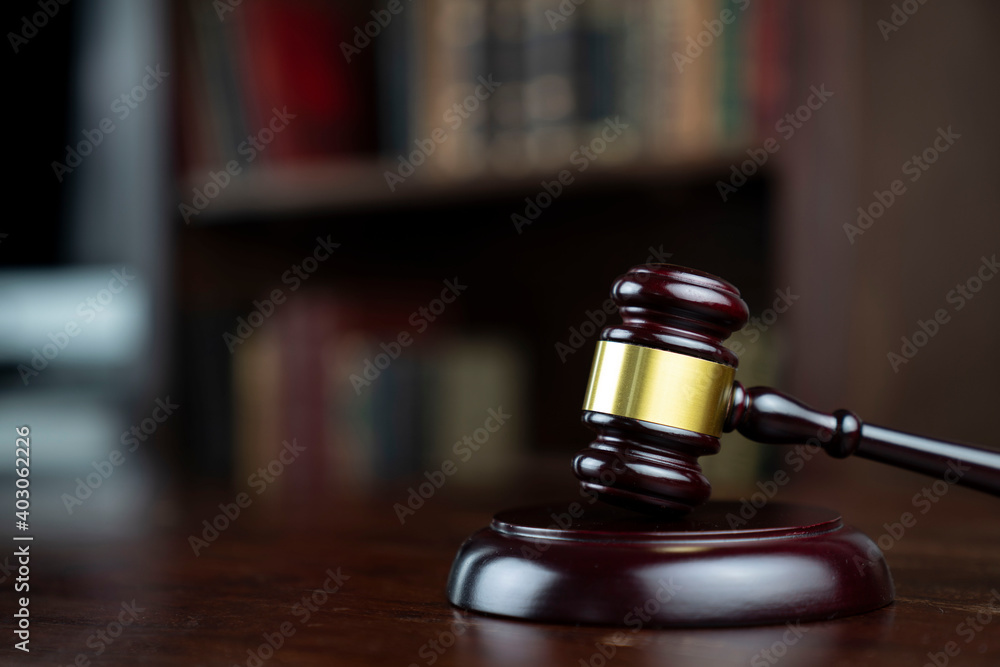 Law theme. Judge chamber. Judge’s gavel on brown desk. Collection of legal books in the bookshelf. Law theme. Judge chamber. Judge’s gavel on brown desk. Collection of legal books in the bookshelf.