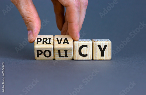 Privacy policy symbol. Hand turns the wooden cube with words 'Privacy policy' on a beautiful grey background. Business and privacy policy concept. Copy space. photo