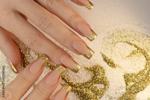 Golden fashionable French manicure on long nails with sequins.