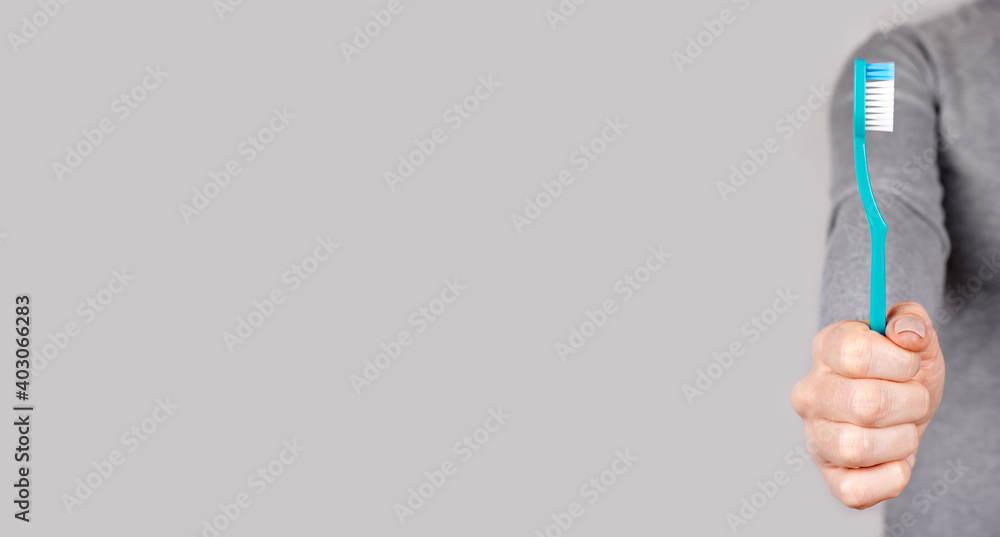 Hand with blue toothbrush on grey background. Hand with blue toothbrush on grey background.