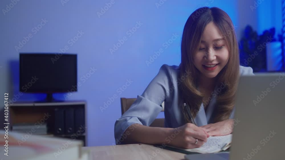 Young Asian woman using laptop computer talking with customer by video call working late night at home Young Asian woman using laptop computer talking with customer by video call working late night at home