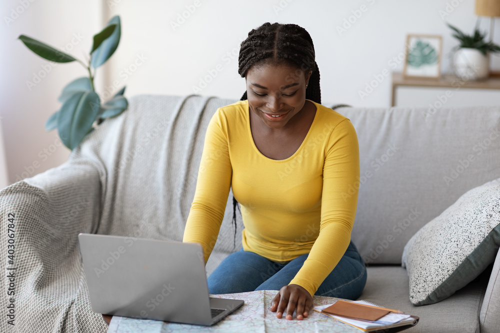 Positive Black Lady Planning Vacation With Laptop And Map At Home - obrazy, fototapety, plakaty 