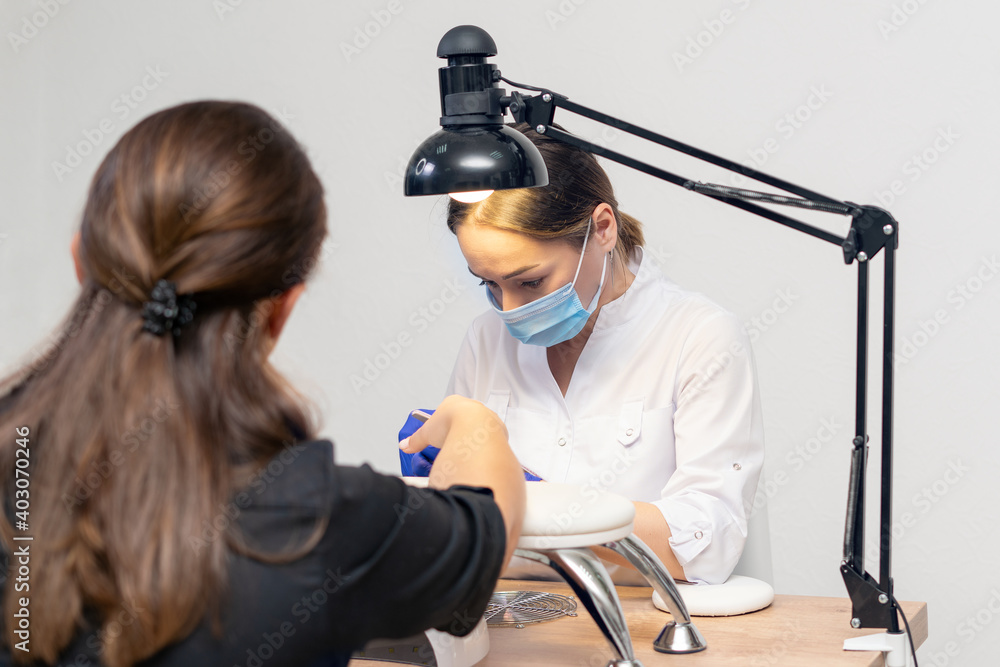 Manicurist doing a manicure in a nail salon using a nail file Manicurist doing a manicure in a nail salon using a nail file