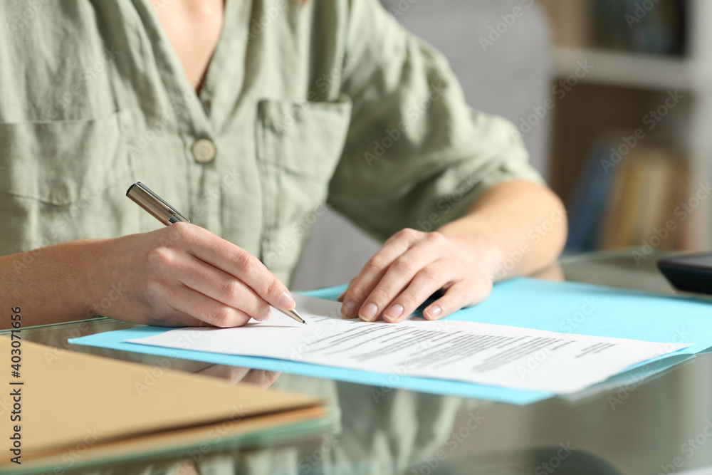 © Antonioguillem - Woman hands signing contract on a glass table at home