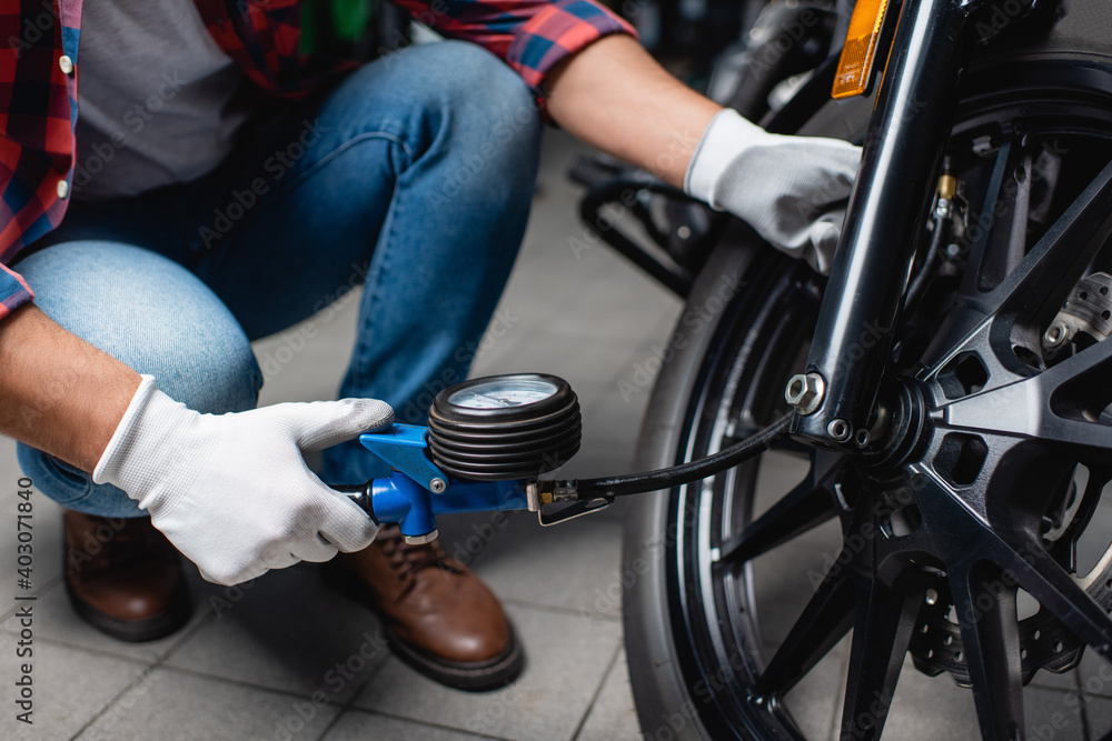 cropped view of technician measuring air pressure in tire of motorbike with manometer, blurred background cropped view of technician measuring air pressure in tire of motorbike with manometer, blurred background