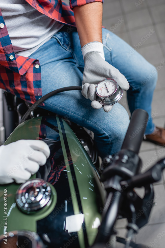 selective focus of manometer in hands of technician measuring air pressure in tire of motorcycle selective focus of manometer in hands of technician measuring air pressure in tire of motorcycle