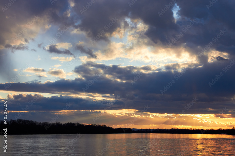 Dramatic sunset cloudy sky over the river at winter season