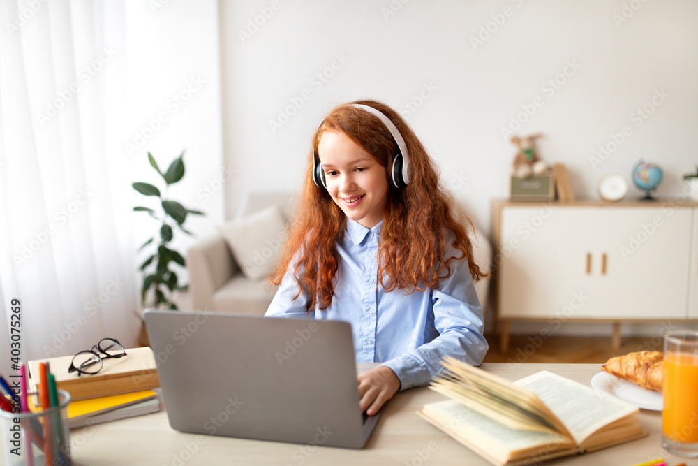Girl wearing headphones using laptop looking at computer Girl wearing headphones using laptop looking at computer