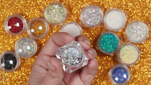 Closeup top view 4k video of shiny chameleon effect flakes for trendy nail design. Different glitters and powders in backgrond.