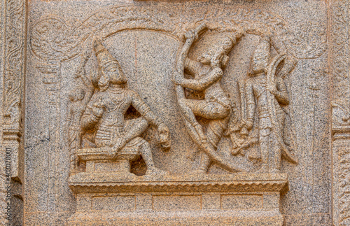 Hampi, Karnataka, India - November 4, 2013: Hazara Rama Temple. Closeup of beige stone damaged sculpture on wall featuring visitors with gifts to the king. © Klodien
