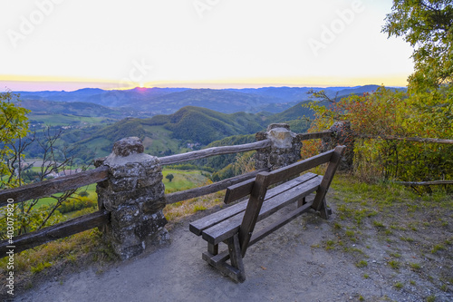 Empty wooden bench on the peak across mountains landscape and sunrise. Meditation, relaxation, calmness concept