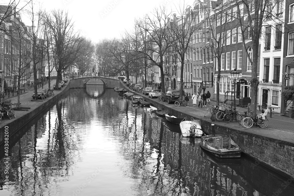 Amsterdam Canal View with Bridge, Winter Trees, Boats and Reflections in Black and White