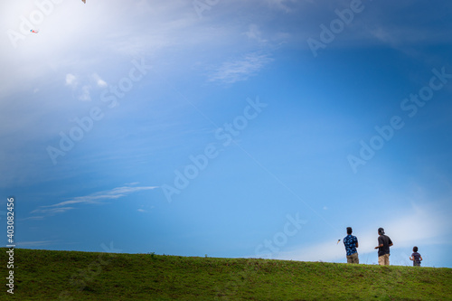 Two boys flying kites in a grassland mountain hill, blue bright sky scenic landscape,
