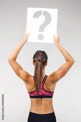 fit girl in sportswear holding question mark sign photo