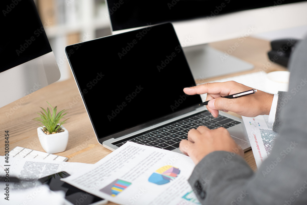 cropped view of trader pointing with finger at laptop with blank screen, blurred foreground cropped view of trader pointing with finger at laptop with blank screen, blurred foreground