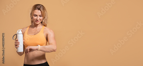 Healthy lifestyle, hydration and modern workout. Smiling muscular adult woman in sports uniform checks pulse © Prostock-studio