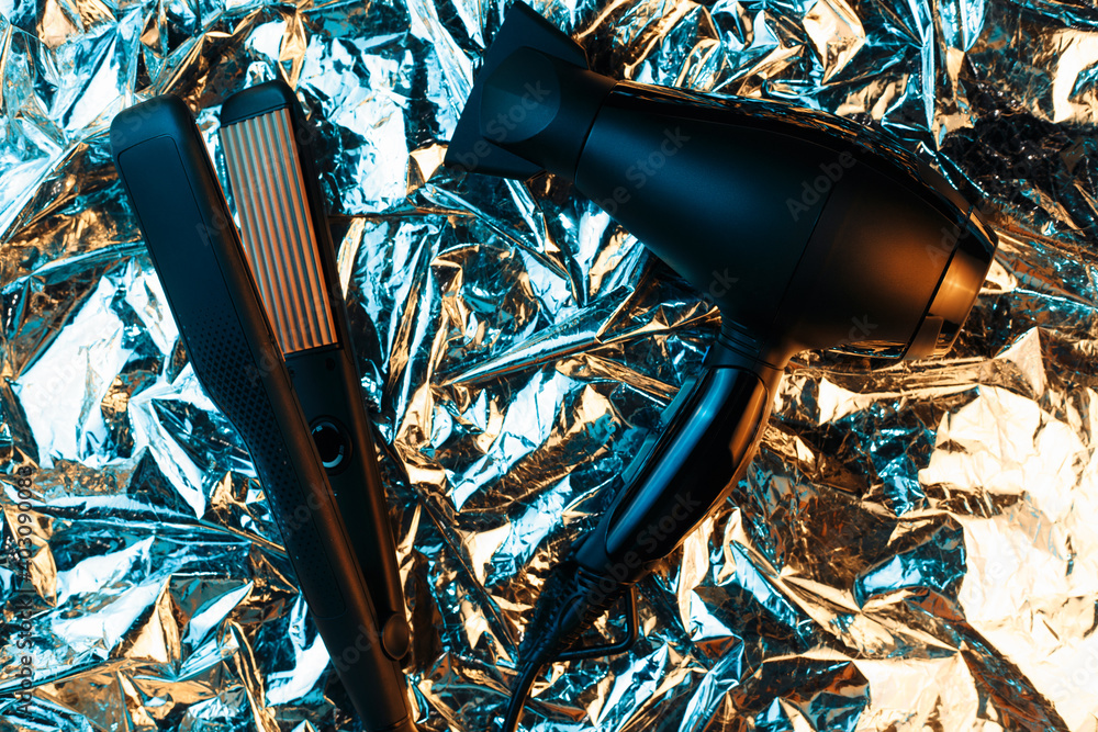 Hair dryer and hair straightener in neon lights on the foil with shiny