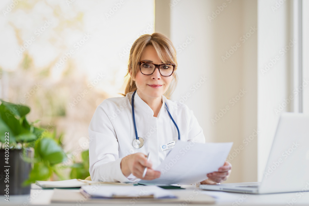 Shot of female doctor sitting at desk and working in doctor's room Shot of female doctor sitting at desk and working in doctor's room