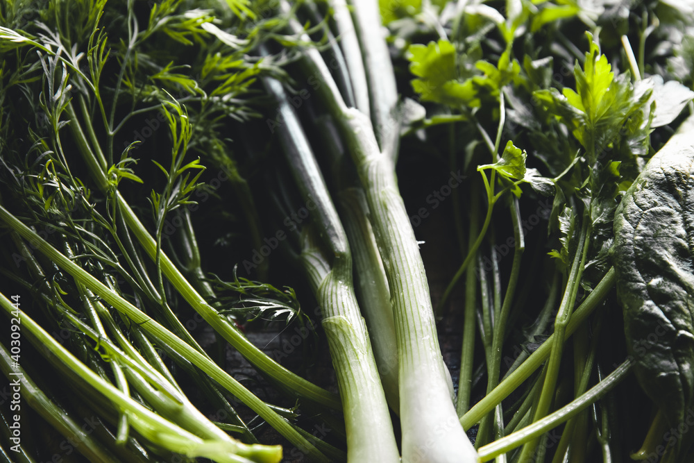 Fototapeta premium Healthy food background. Fresh spinach, dill, parsley, sorrel, green onions, rustic cutting board