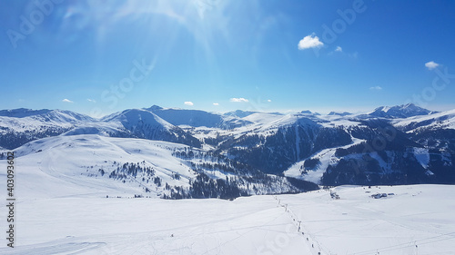 A panoramic view on the snow covered slopes of Innerkrems, Austria. The slopes are ready for skiing. Cloudless, blue sky. Many Alpine chains in the back. Winter wonderland. Fresh, powder snow.