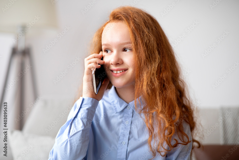 Smiling red-haired girl talking on cell phone