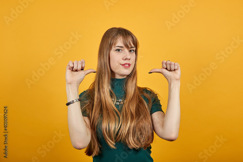 Pointing thumb over shoulder at blank space isolated. Astonished points with thumb aside. Look here. Studio photo portrait of satisfied sure, recommending cheerful nice human offering new solution