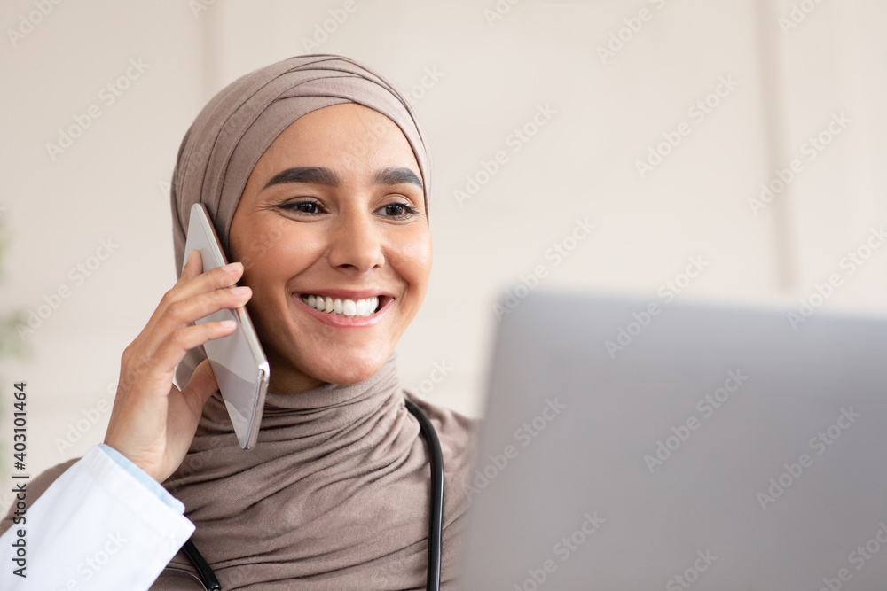 Closeup of female doctor having phone call, using laptop Closeup of female doctor having phone call, using laptop