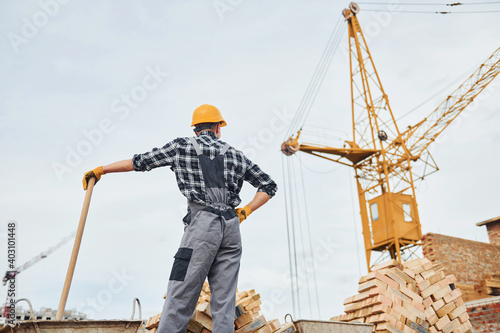 With shovel in hands. Construction worker in uniform and safety equipment have job on building