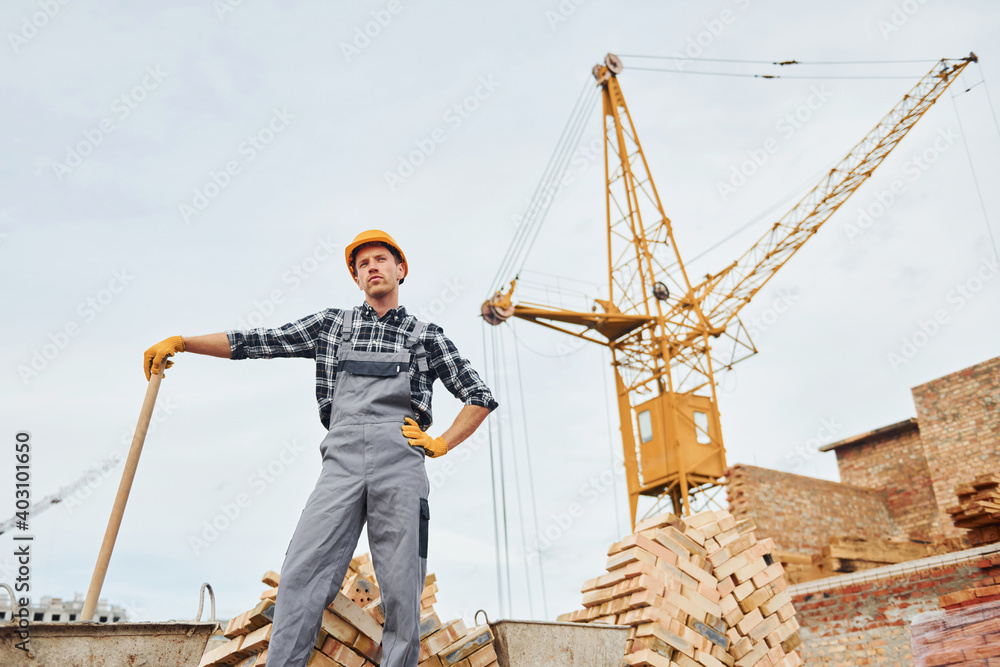 With shovel in hands. Construction worker in uniform and safety equipment have job on building With shovel in hands. Construction worker in uniform and safety equipment have job on building