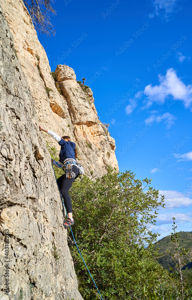 Vertical photo of a young climber climbing the mountain in a beautiful place