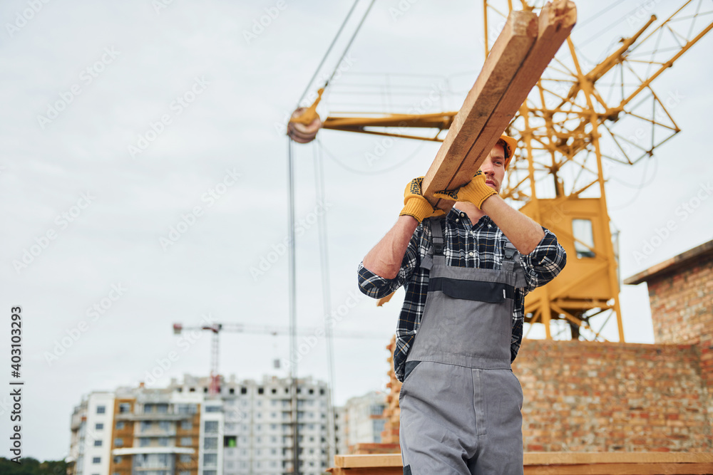 Transporting wooden boards. Construction worker in uniform and safety equipment have job on building Transporting wooden boards. Construction worker in uniform and safety equipment have job on building