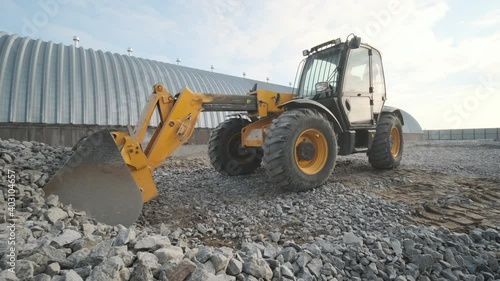 Tractor moves rubble to truck. Excavator-loader rakes rubble from pile at construction site and loads dump truck. Clearing site
