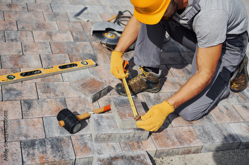 Measuring process. Male worker in yellow colored uniform have job with pavement