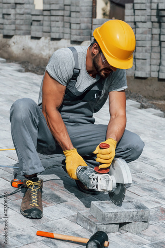 Concentrated at work. Man in yellow colored uniform have job with pavement