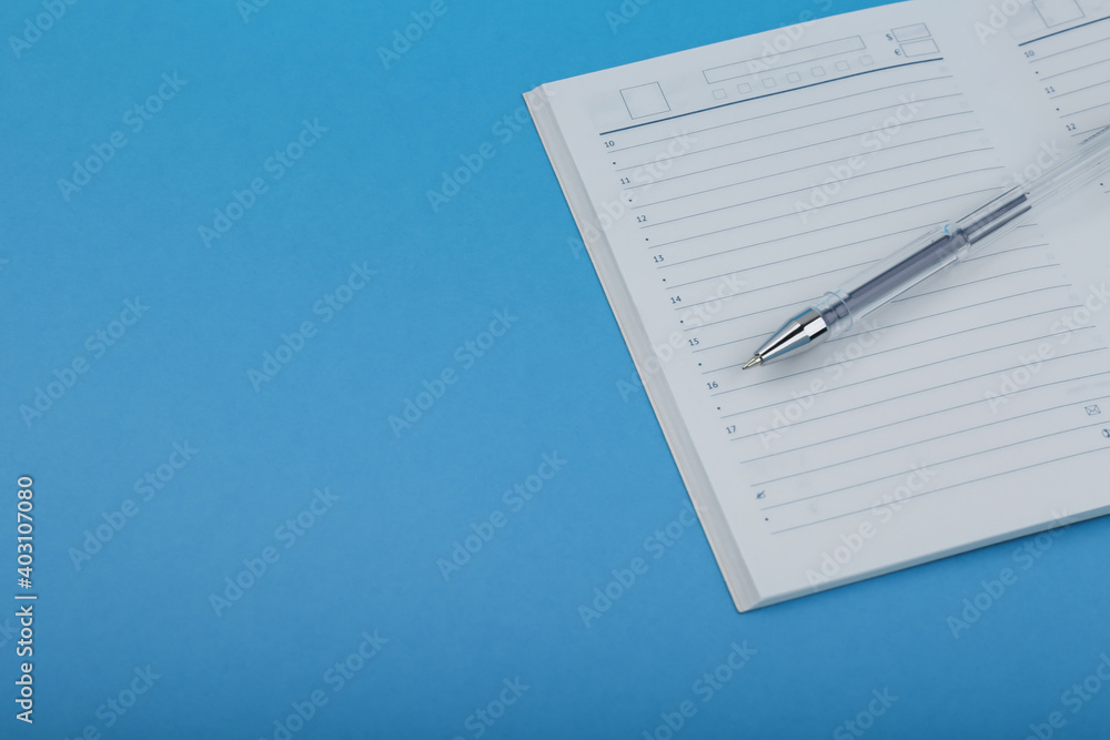 daily planner and pen on a blue background daily planner and pen on a blue background