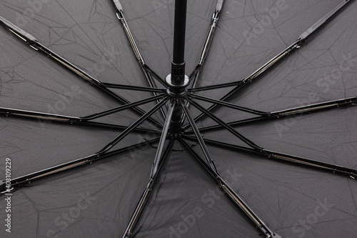 The inner side of an open black men's umbrella, part of the umbrella dome opening mechanism. Close-up.