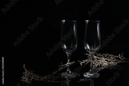 Two empty glasses of champagne and Christmas or New Year decoration on a black background. Romantic dinner. Winter holiday concept.