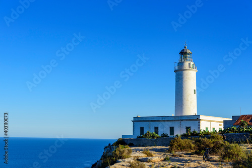 Faro marítimo en acantilado con cielo y mar azul