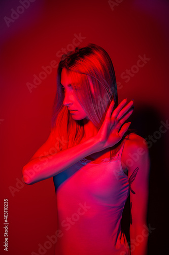 Anonymous woman covering face with hand in red neon light