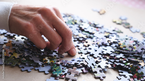 woman doing jigsaw puzzle on the craft paper.Woman's hand and puzzle pieces.