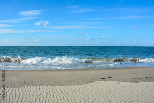 Waves on sand beach with blue sky © Claudia Evans 