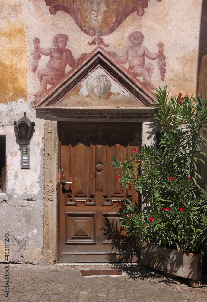 Fototapeta premium Renaissance portal with pediment and baroque fresco painting at the Thaler building facade in the old town of Lana in South Tyrol, Italy