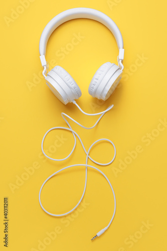 Stylish white headphone on yellow background. Music concept.