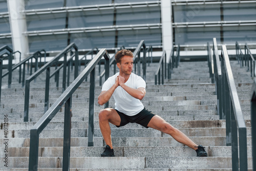 Young man in sportive clothes have workout outdoors at daytime