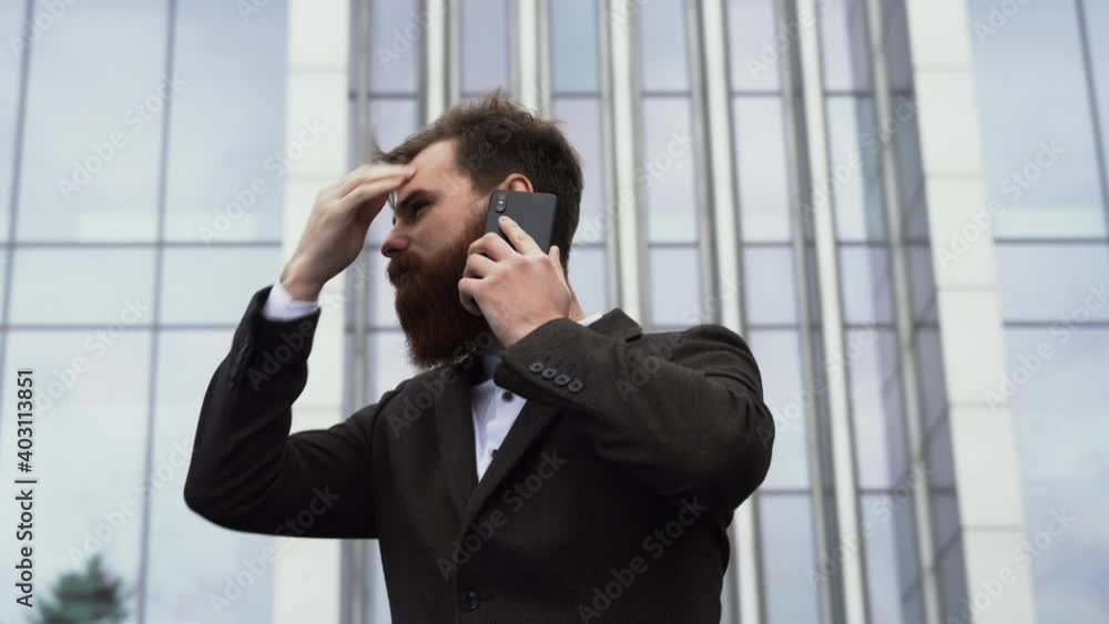 Businessman talking on the phone in financial district. Portrait of a Young urban professional man using smart phone over office building. Business man talking on his smartphone outdoors. Technology. Businessman talking on the phone in financial district. Portrait of a Young urban professional man using smart phone over office building. Business man talking on his smartphone outdoors. Technology.