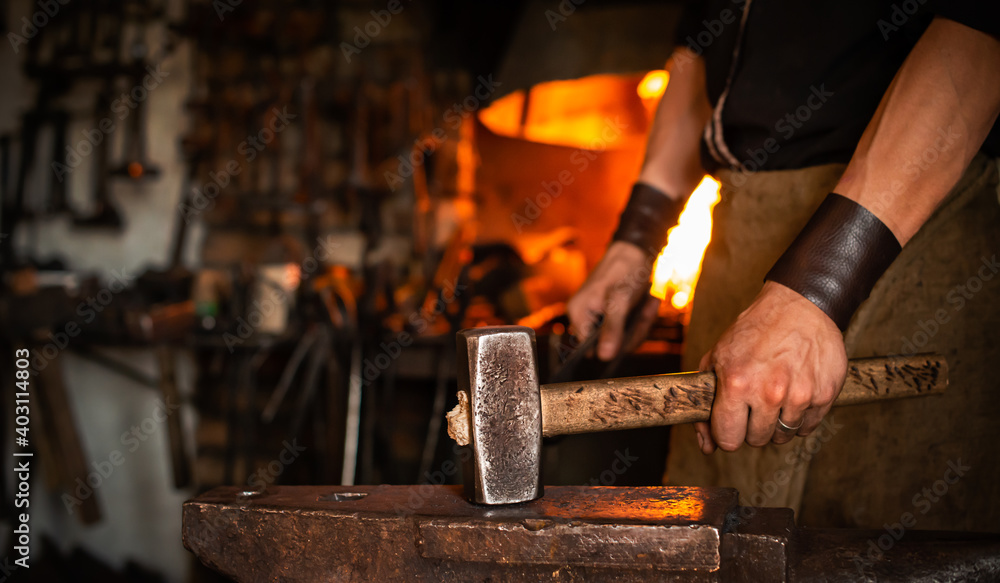 blacksmith performs the forging of hot glowing metal on the anvil blacksmith performs the forging of hot glowing metal on the anvil