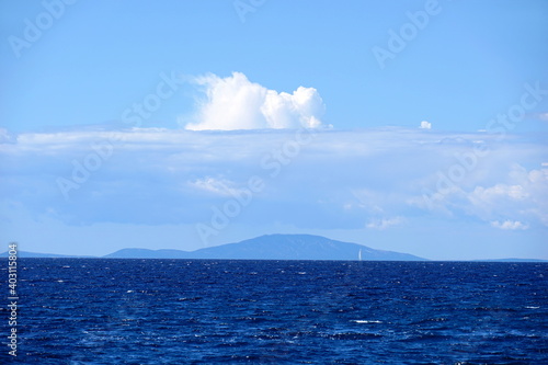 Beautiful view to sea horizon with indigo blue color tone of water and light blue sky with clouds